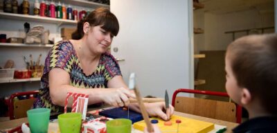 Pædagog hjælper til med at hamre søm i et bræt, der skal blive til et kunstværk. Fagbevægelsens Hovedorganisation