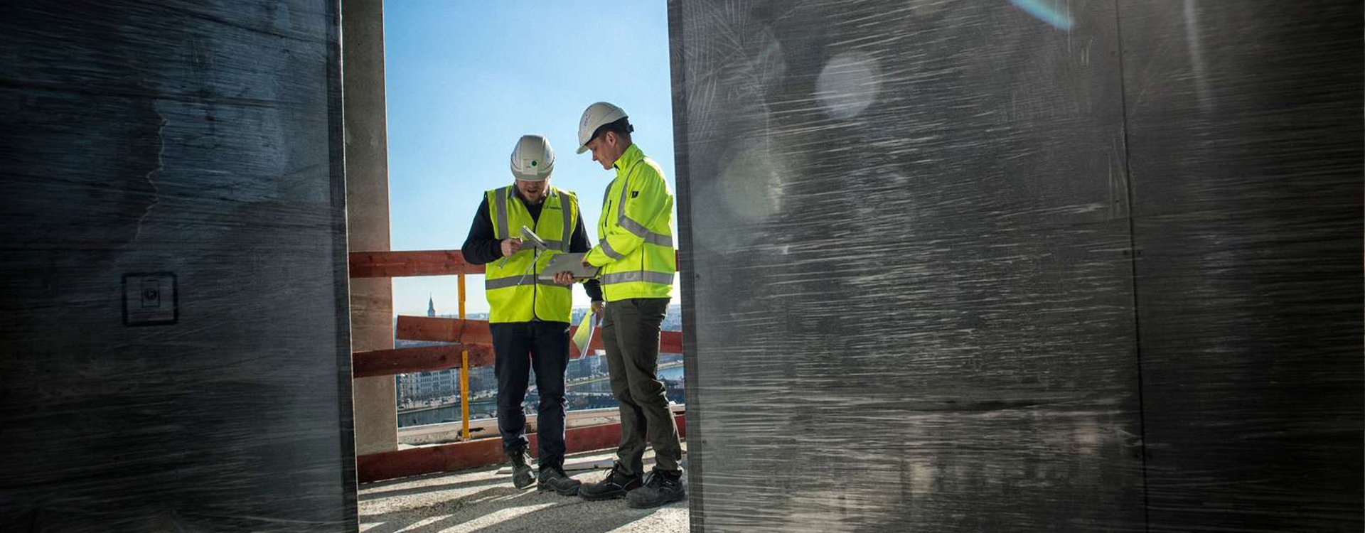 Fagbevægelsens Hovedorganisation, 2 byggekonstruktører taler sammen på byggeplads, Ludvigsen
