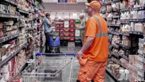 Mand i orange arbejdstøj med indkøbsvogn i supermarked
