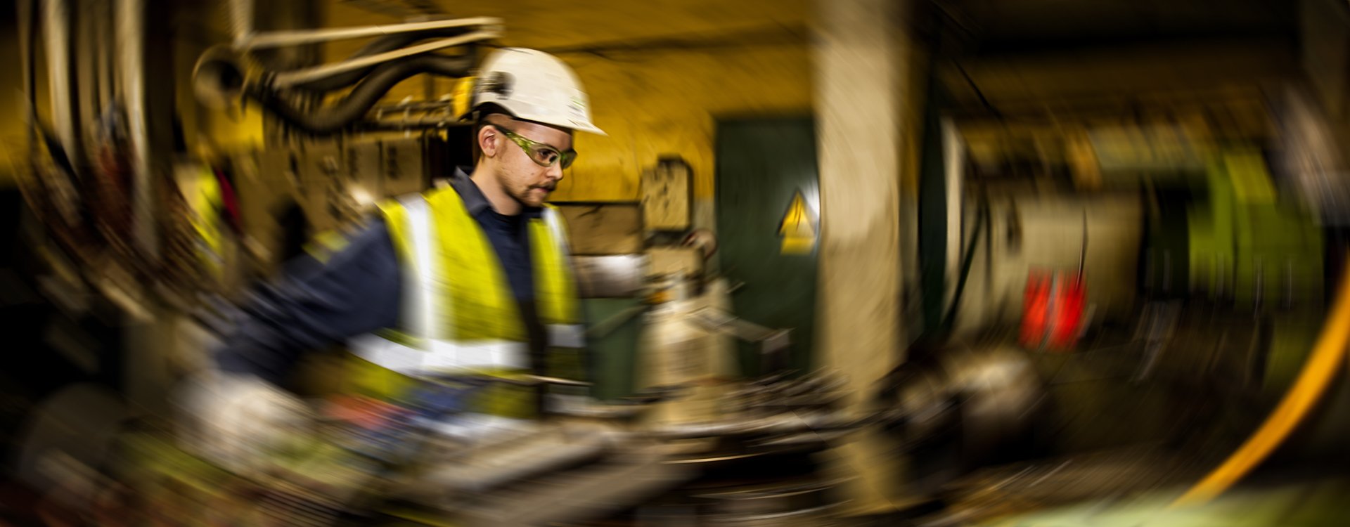 Ung mandlig maskinarbejder på virksomheden Nordic Sukkermed hjelm i uskarpe omgivelser