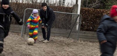 Pædagoger på arbejde i vuggestue. De spiller fodbold i gården