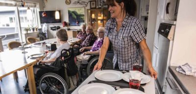 Social- og sunndhedsassistent på arbejde på plejehjem. Her serveres der mad i fællesstuen.